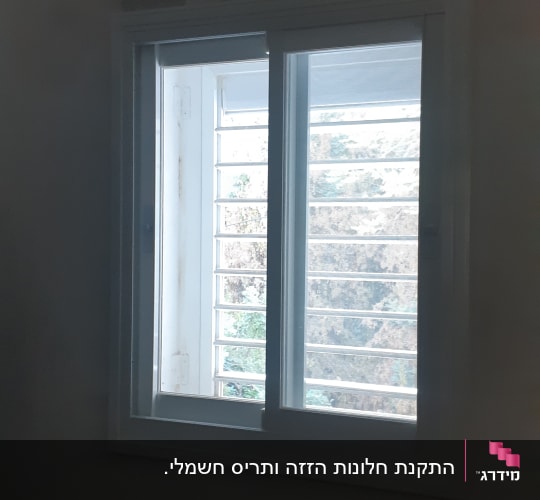 חלון אלומיניום לבן בעל כנפי הזזה ורשת מותקן בחדר